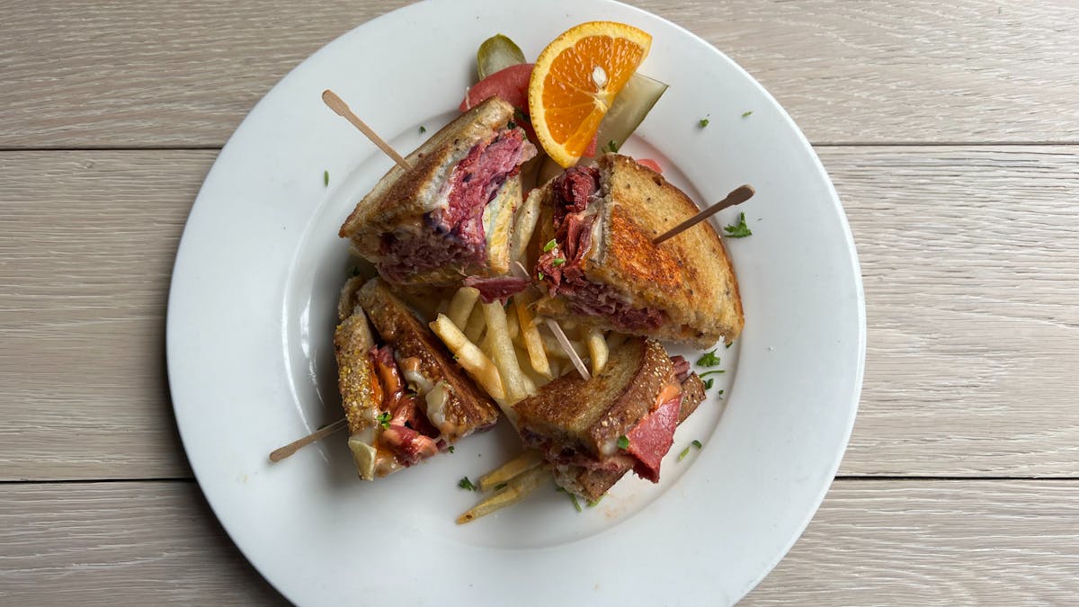 Grilled Reuben cut into quarters, with corned beef, melted cheese and sauerkraut.
